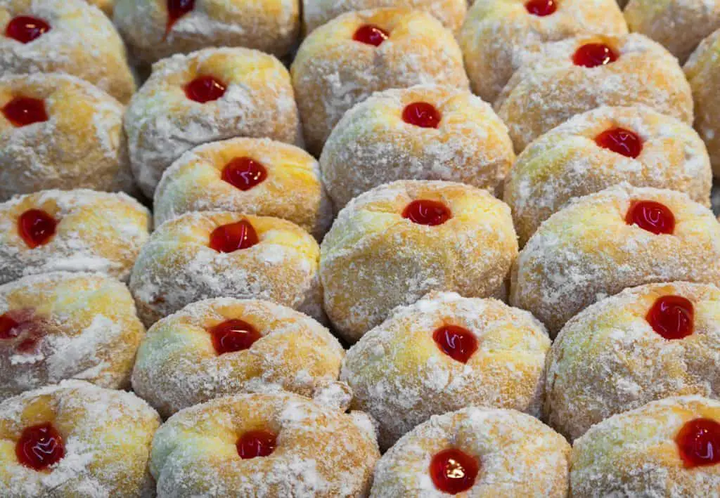 Rows of jelly donuts on a cookie sheet.